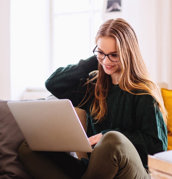 lány a kanapén, miközben a laptopon elindul a Norton 360 Standard.