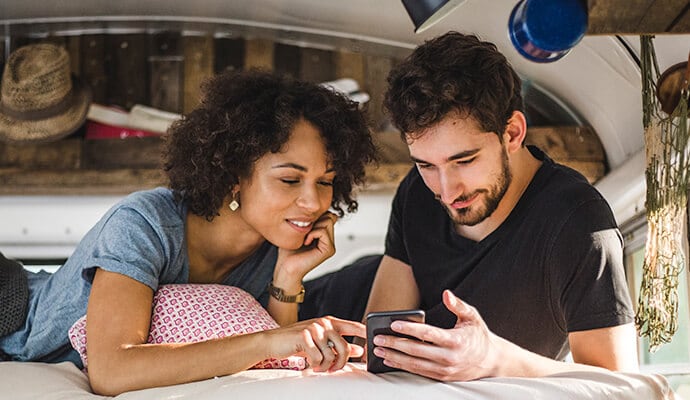 férfi eszik és a mobiltelefonját nézi, miközben elindul a Norton 360 Standard program.